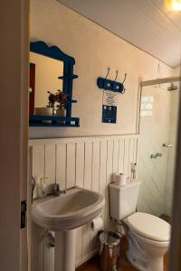 ein Badezimmer mit einem Waschbecken, einem WC und einem Spiegel in der Unterkunft Pousada Lagoa Azul Marina in Capitólio