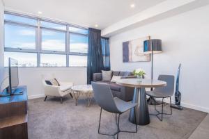 a living room with a table and chairs and a couch at Train Station Access! 1Bed1Bath APT at Chatswood in Sydney