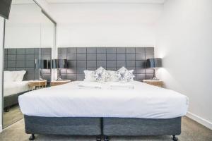 a bedroom with a large white bed with two mirrors at Train Station Access! 1Bed1Bath APT at Chatswood in Sydney