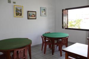 two tables and chairs in a room with a window at Associação Sabesp Bertioga - SP in Bertioga