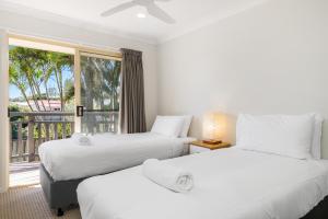 two beds in a room with a balcony at Bayside Court Apartments in Byron Bay