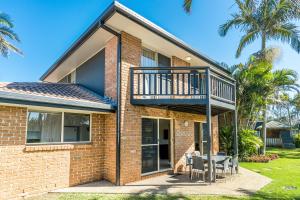 a brick house with a balcony and a table and chairs at Bayside Court Apartments in Byron Bay