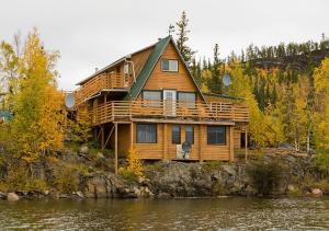 a wooden house on the shore of a lake at Yellow Dog Lodge, Inc. in Yellowknife