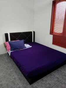 een groot bed met paarse lakens in een kamer bij Homestay Idaman di Kuala Terengganu dengan 2 Bilik Aircond - Harga utk 1 rumah in Kuala Terengganu