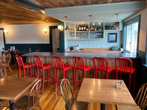 um restaurante com cadeiras vermelhas e um bar em The Craignair Inn & Causeway Restaurant em Spruce Head