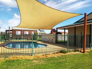 a fence with a pool in front of a house at Holbrook Motor Village in Holbrook