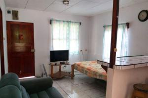 een woonkamer met een bank, een bed en een televisie bij Restaurante y cabinas Sudy in Carara
