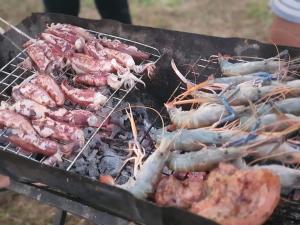 a bunch of meat and shrimp cooking on a grill at บ้านในสายหมอกบุญแจ้งโฮมสเตย์ in Khao Kho
