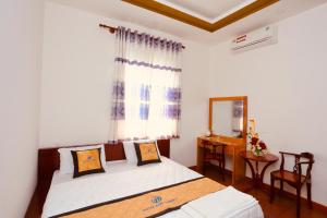 a bedroom with a bed and a mirror and a window at Hotel Đức Thành in Con Dao