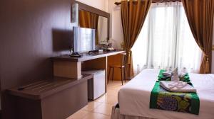 a hotel room with a bed and a desk with a television at Sokdee City Hotel in Vientiane