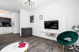 a living room with a tv and a green chair at Sleepway Apartments- Garbary 100-46 in Poznań