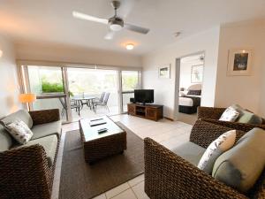 a living room with two couches and a television at Beach Terraces in Port Douglas