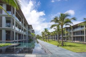 uma vista exterior de um edifício com piscina e palmeiras em Luxury Oceanfront_pool access apartment em Praia de Mai Khao