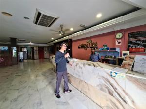 un hombre parado en un mostrador en un restaurante en Anika Inn - Kluang, en Keluang