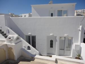 a white house with white stairs and a building at Triena Apartments in Fira