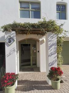 a white house with two potted plants in front of a door at Langebaan Paradise Beach Self Catering 5 Elara in Langebaan