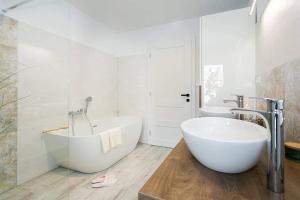 a bathroom with a large white tub and two sinks at The Luxury Penthouse in Banská Bystrica