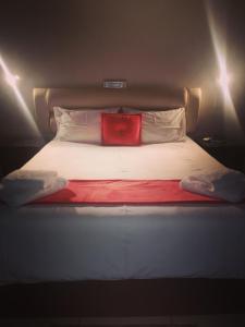 Una cama con una almohada roja encima. en AAA Rose Garden Guesthouse, en Mookgophong