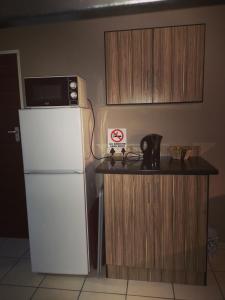 a kitchen with a refrigerator and a counter with a microwave at AAA Rose Garden Guesthouse in Naboomspruit