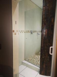 a shower with a glass door in a bathroom at AAA Rose Garden Guesthouse in Naboomspruit
