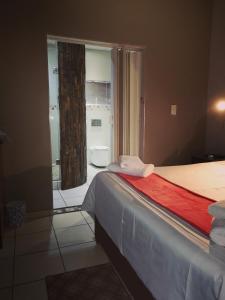 a bedroom with a bed and a bathroom with a shower at AAA Rose Garden Guesthouse in Naboomspruit