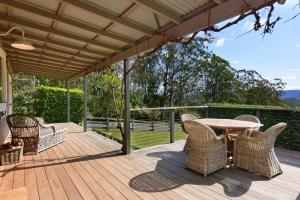 a wooden deck with a table and chairs on it at Maple Cottage in Kangaroo Valley