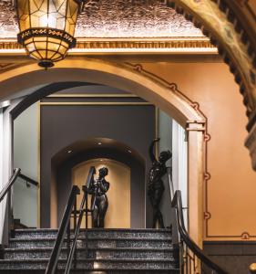 an archway leading up to a staircase in a building with statues at Hotel Bristol in Oslo