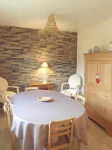 d'une salle à manger avec une table, des chaises et un mur en briques. dans l'établissement le petit jour classé 3 étoiles Maison 6 pers climatisée - Audenge - Bassin d'Arcachon, à Audenge