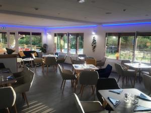 a restaurant with tables and chairs and windows at Hôtel du Lac d'Arjuzanx in Arjuzanx