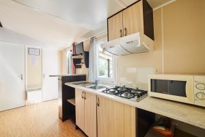 a small kitchen with a microwave and a stove at Alannia Costa Dorada in Platja de l’Almadrava