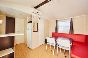 a room with a red couch and white chairs at Alannia Costa Dorada in Platja de l’Almadrava