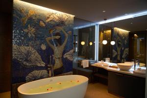 a bathroom with a tub and a mosaic wall at HOME Hotel in Ho Chi Minh City