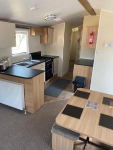 a kitchen with a sink and a table in a room at KellysHolidayHomes Atlas 3 bedrooms caravan in Weeley