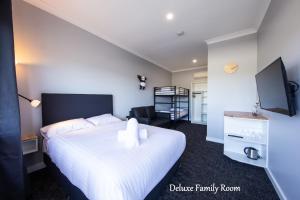 a bedroom with a large white bed and a living room at Vikas in Jindabyne