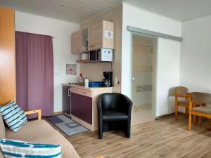 ein kleines Zimmer mit einer Küche, einem Sofa und einem Stuhl in der Unterkunft Monteurzimmer mit Singleküche in Kaufing