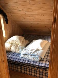 a bed in a wooden cabin with two pillows at Ramsbu Hovden Fjellpark sen utsjekk in Hovden