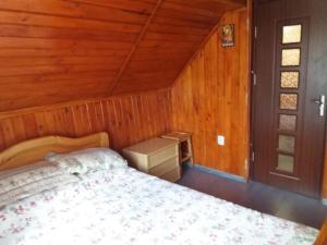 ein Schlafzimmer mit einem Bett in einem Holzzimmer in der Unterkunft Casuta Paterau Cheia, Prahova in Cheia