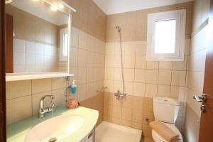 a bathroom with a sink and a toilet and a mirror at Evridiki's Villas in Agios Nikitas