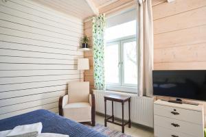 1 dormitorio con 1 cama, TV y silla en Köpmans en Nauvo