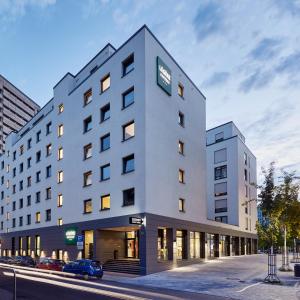 un grand bâtiment blanc avec une voiture garée devant. dans l'établissement LÉGÈRE EXPRESS Bielefeld, à Bielefeld