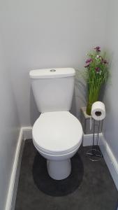 a white toilet in a bathroom with flowers at Mango Lodge in Kent