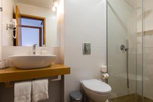 a bathroom with a sink and a toilet and a shower at Hotel Arcanjo in Rosário-Lagoa