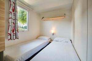 two beds in a small room with a window at Alannia Costa Dorada in Platja de l’Almadrava