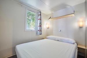 a white bed in a room with a window at Alannia Costa Dorada in Platja de l’Almadrava