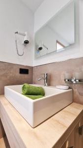 a white bathroom sink with a green towel in it at Sunshine Appartements in Fiss