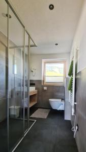 a bathroom with a shower and a toilet and a window at Sunshine Appartements in Fiss