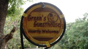 a wooden wine barrel sign hanging from a tree at Green's Guest House in Auroville