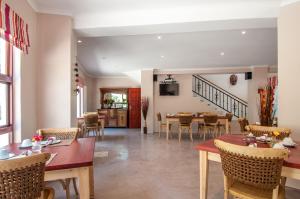 a dining room and living room with tables and chairs at Wind-Rose Guest House in Gordonʼs Bay