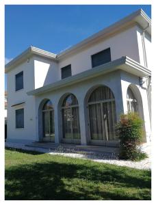 Casa blanca con ventanas grandes y césped en Seven Suites Pieve, en Pieve di Soligo