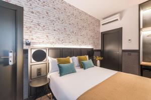 een slaapkamer met een groot wit bed en een bakstenen muur bij BYPILLOW San Mamés in Bilbao